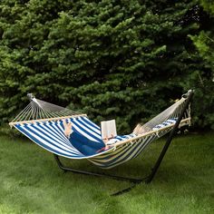 a blue and white striped hammock with a laptop on it in the grass