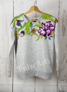 This listing for made to order amazing hand painted women sweatshirt with flowers and butterflies. Ideal for colder days. Sweatshirt is very pleasant to the touch and warm. Will make a nice present for her. I only using best quality textile paint. Machine wash inside out at 30 degrees. Sweatshirt painted at both sides front and back with colorful flowers. Please allow 2-3 weeks for ordering clothing, painting and  dispatch. Please message if it's a gift so it will come gift wrapped. If you like my work but it is not your size please contact me and I will be happy to do something special just for you by your own requirements. I can buy sweatshirt/ denim/ t-shirt myself of your size or you can send me your item or buy online  clothing yourself just fill in my address for delivery. If you wan Cheap Artistic Tops As Gifts, Painted Sweatshirt, Flowery Outfits, Paint Sweatshirt, Painted Canvas Shoes, Personalized Jacket, Hand Painted Denim Jacket, Hand Painted Clothing, Painted Denim Jacket