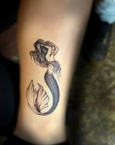 a woman's leg with a mermaid tattoo on the side of her body,