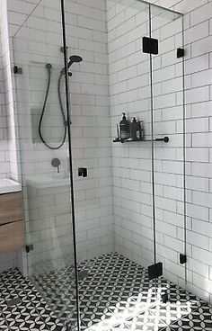 a bathroom with black and white tile flooring, shower head and toilet in the corner