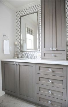 a bathroom with gray cabinets and a large mirror