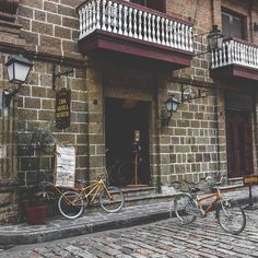 two bikes are parked in front of a brick building with balconies on the windows