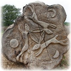 a tree trunk with carvings on it in the grass