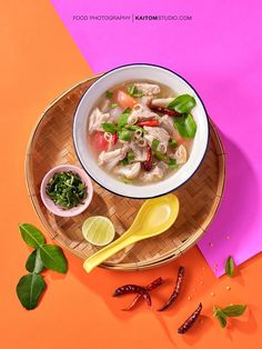 an overhead view of a bowl of soup on a plate with spoons and herbs