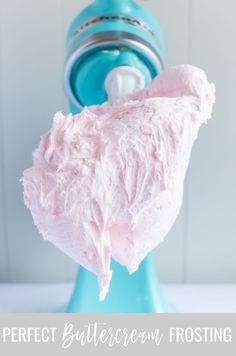 a blue blender filled with pink frosting next to a white wall and the words perfect buttercream frosting on it