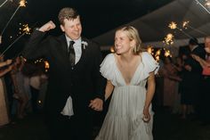 a bride and groom walk through sparklers at their wedding