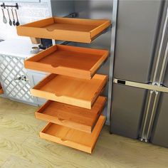 three wooden drawers are stacked on top of each other in front of a stainless steel refrigerator