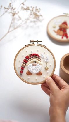 someone is holding up a cross stitch christmas ornament in front of some crafting supplies