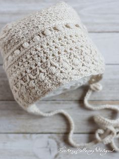 a white crocheted hat on top of a wooden floor next to a pair of scissors