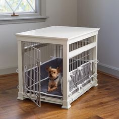 a small dog is sitting in a cage on the floor next to a table and window