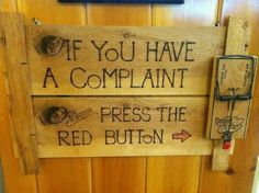 a wooden sign that says if you have a complaint press the red button