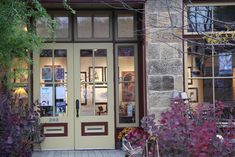 the front entrance to a store with flowers and plants