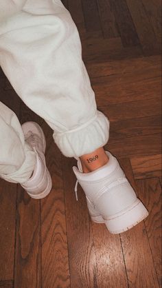 a person's foot with the word love tattooed on their left ankle and white sneakers