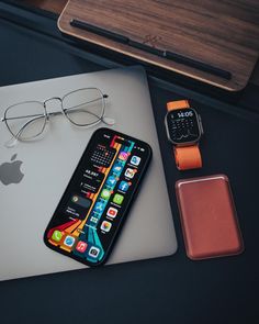 an apple watch, cell phone and glasses on a desk