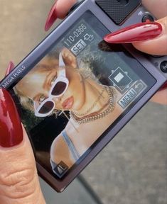 a woman with red nails holding up a cell phone