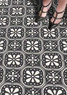 a woman in high heels standing on a black and white tile floor