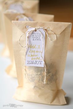 three bags with tags tied to them sitting on a white tablecloth covered table cloth