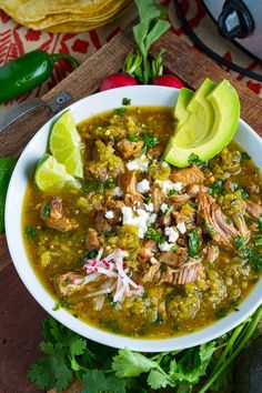 a white bowl filled with chicken and tortilla soup on top of a wooden cutting board