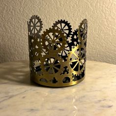 a gold crown with gears on it sitting on a marble counter top next to a white wall