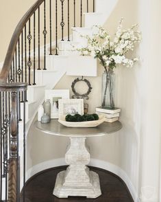 a vase with flowers on top of a table next to a stair case and railing