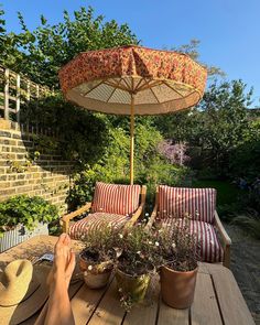 a person sitting at a table with an umbrella over their head and some plants on it