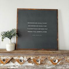 a chalkboard with a quote on it next to a potted plant in a vase