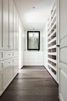 a long hallway with white cabinets and drawers on both sides, leading to a dressing room