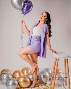 a woman is posing with balloons and confetti