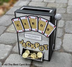 a card box with some gold coins in it on the ground next to a brick walkway