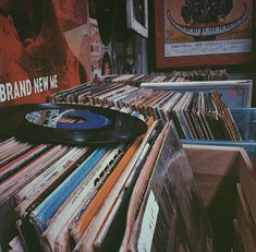 an old record player sitting on top of a table full of records in front of a poster