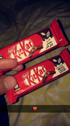 someone holding two bars of kitkat chocolate