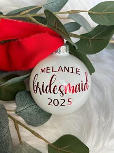 a bridesmaid ornament hanging from a tree with leaves and red rose