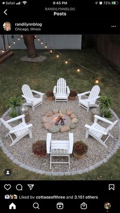 a fire pit surrounded by white chairs in the middle of a yard with string lights