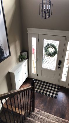 an overhead view of a staircase with a wreath on the door and a checkered rug