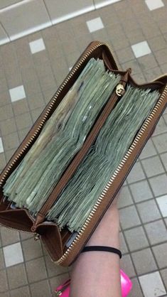 a wallet filled with money sitting on top of a tiled floor