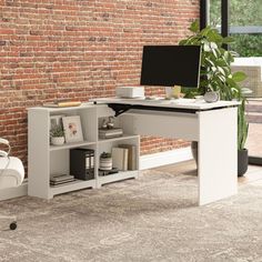 a computer desk with a monitor and keyboard on it in front of a brick wall