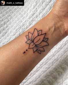 a lotus flower tattoo on the wrist and arm is shown in black ink, with tiny dots