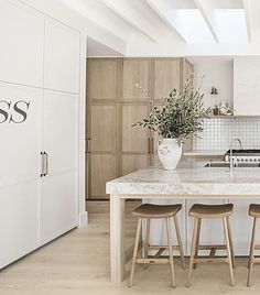 a kitchen with an island and stools in front of the counter top that has a plant on it