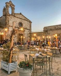 an outdoor dining area with tables and chairs in front of a church at night time