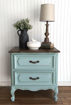 a blue dresser with two drawers and a lamp on top