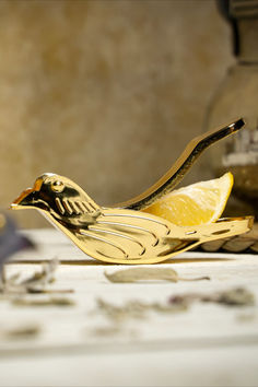 a golden bird figurine sitting on top of a table next to a lemon slice