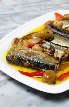 a white plate topped with fish and veggies on top of a marble table