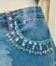 the back of a woman's jeans with blue jewels on it