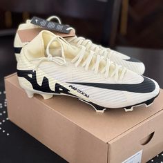 a pair of white and black nike soccer cleats sitting on top of a box