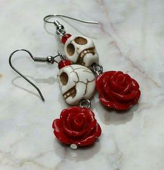 three skulls with red roses on them are sitting on a marble counter top and one is dangling from the earwires