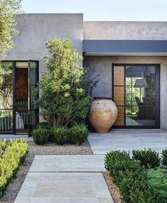 a large vase sitting in the middle of a garden next to a tall planter