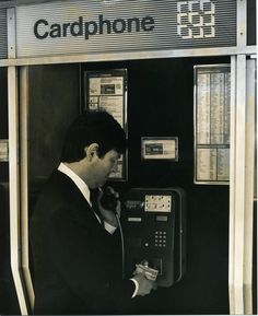 a man in suit and tie using a phone at a payphone booth on the street