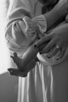 a black and white photo of a woman holding a baby in her arms with both hands