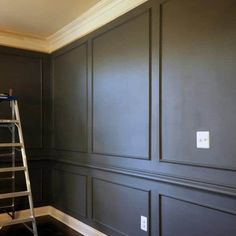 a ladder is in the corner of a room with dark green walls and white trim