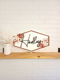 there is a sign that says hadley on the shelf next to a vase with flowers